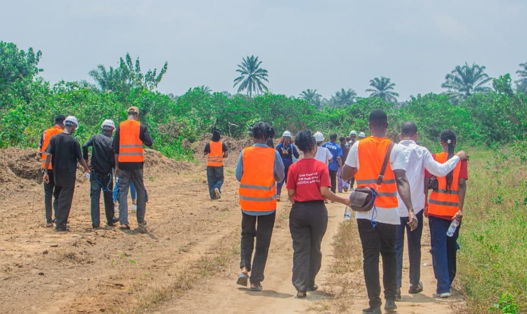Site tour group walking the access road through Lucent City